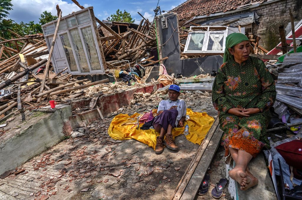 Ela (58) bersama keluarganya duduk di depan rumahnya yang runtuh akibat gempa di Kampung Longkewang, Desa Gasol, Cugenang, Kabupaten Cianjur, Jawa Barat, Selasa (22/11/2022). Kondisi kerusakan akibat gempa yang melanda Cianjur pada Senin (22/11/2022) terlihat di sejumlah wilayah desa yang terdampak. 