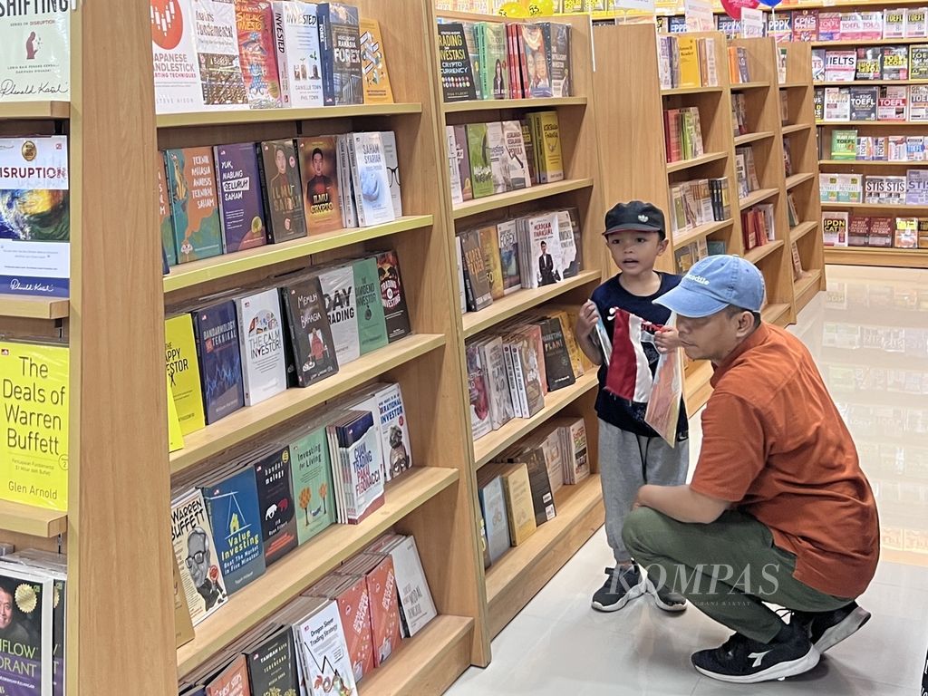 Seorang anak bersama ayahnya memilih buku di Toko Buku Gramedia Pettarani, Makassar, Sulawesi Selatan, Kamis (2/2/2023).