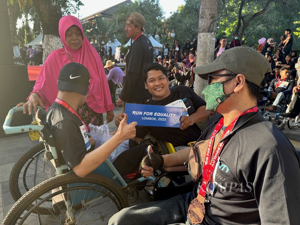 Seorang peserta pengguna kursi roda memperlihatkan tulisan "Run For Equality" seusai mengikuti kegiatan lari dan jalan gembira bersama di Mataram, Nusa Tenggara Barat, Minggu (30/7/2023) pagi. 