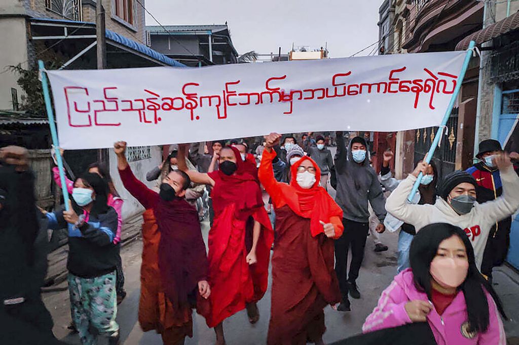 Para pemuda aktivis dan biarawan Buddha berpartisipasi dalam protes anti-pemerintahan militer sambil memegang spanduk bertuliskan bahasa Myanmar yang berarti, "Siapa yang berani berada di sisi yang berlawanan dengan kehendak rakyat".  