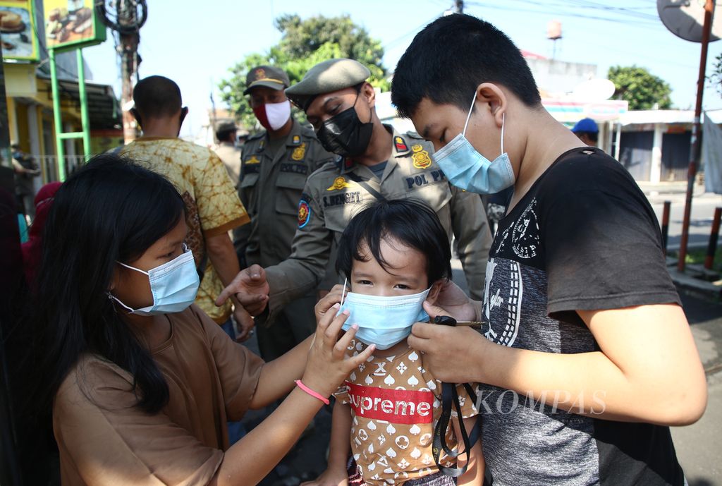 Anak-anak yang terjaring operasi yustisi tertib masker mengenakan masker pemberian petugas di kawasan Pesanggrahan, Jakarta Selatan, Kamis (15/4/2021).  Pemerintah per 18 Mei 2022 telah melonggarkan penggunaan masker bagi masyarakat yang beraktivitas di ruang terbuka yang tidak padat orang.
