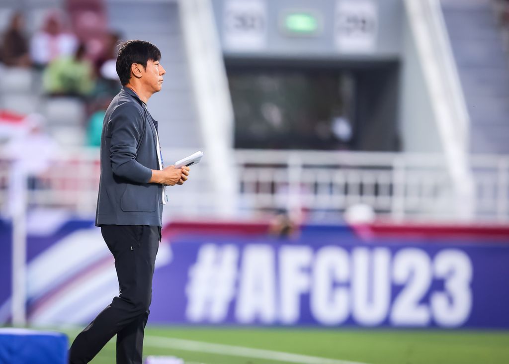 Pelatih Indonesia U-23 Shin Tae-yong memegang buku catatan ketika mengamati performa anak asuhannya menghadapi Australia pada laga Grup A Piala Asia U-23 2024, Kamis (18/4/2024), di Stadion Abdullah bin Khalifa, Doha.