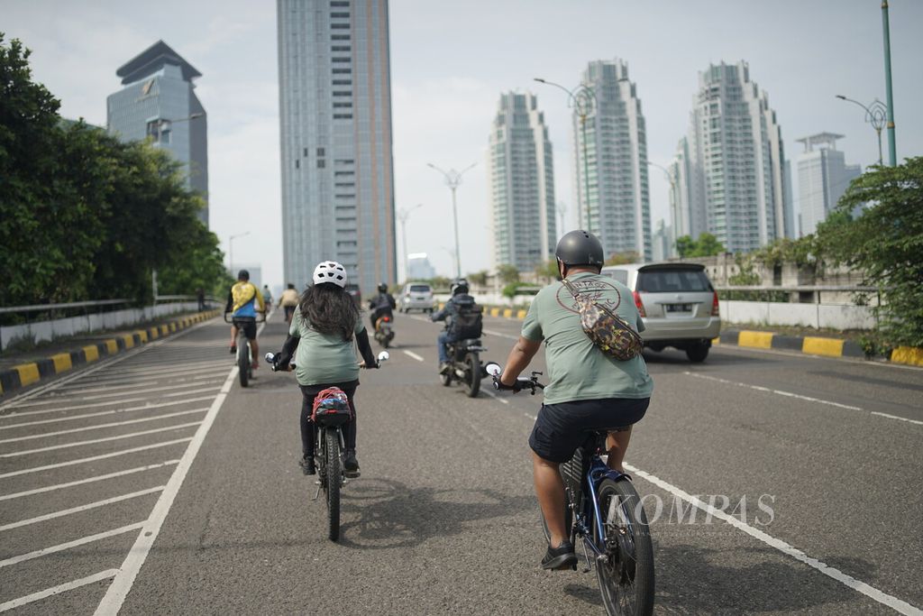 Anggota komunitas pemilik sepeda listrik Vintage Electric melintasi jembatan di kawasan Kuningan, Jakarta, Minggu (9/10/2022). 