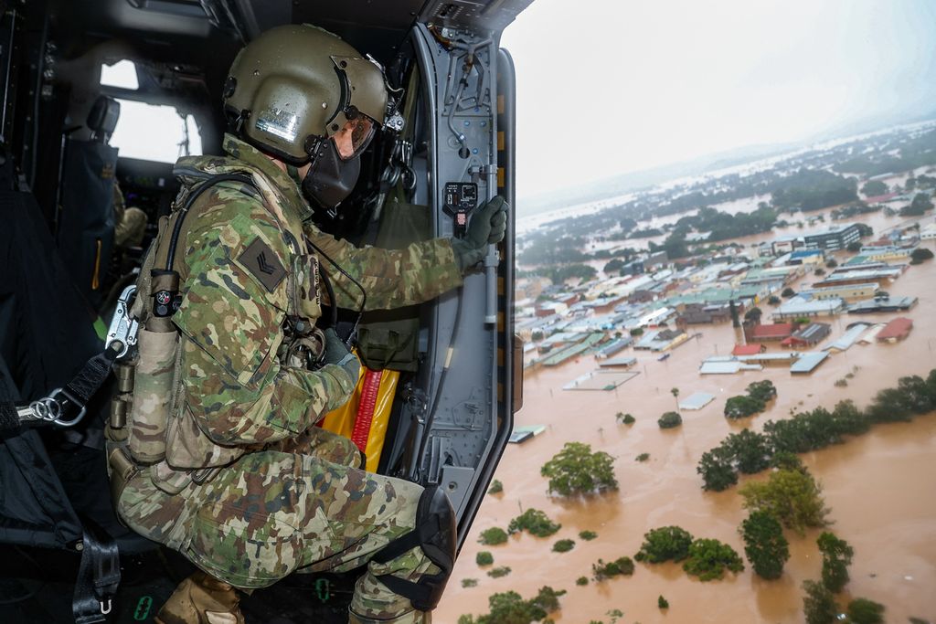 Foto yang dirilis pada 3 Maret 2022 menunjukkan seorang anggota Angkatan Bersenjata Australia, Sersan Rick Scott dari Sekolah Penerbangan Angkatan Bersenjata, memantau banjir dari helikopter MRH-90 Taipan di atas kota Lismore di New South Wales, Australia saat Operasi Bantuan Banjir 2022. 