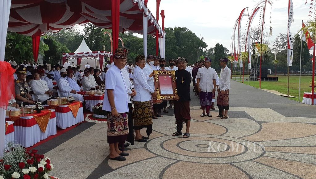 Gubernur Bali Wayan Koster menyerahkan piagam penghargaan Dharma Kusuma kepada I Nyoman Windha (kanan), komposer karawitan asal Gianyar, serangkaian dengan peringatan hari jadi ke-64 Provinsi Bali di Lapangan Puputan Margarana Niti Mandala Renon, Kota Denpasar, Minggu (14/8/2022).