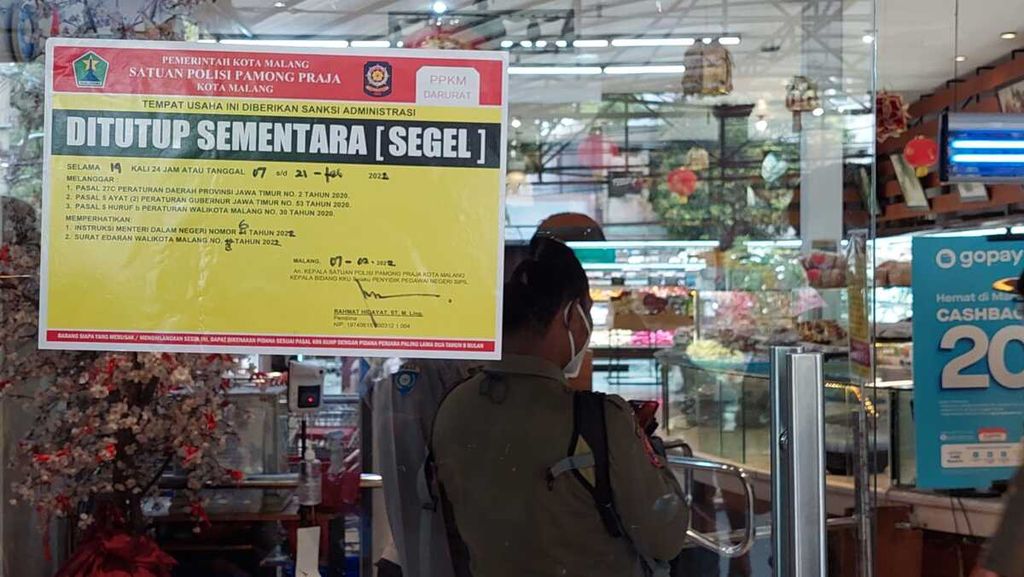 Petugas menutup sementara supermarket di Jalan Semeru, Kota Malang, Jawa Timur, Senin (7/2/2022). Satu dari 30 karyawan di sana terpapar Covid-19 setelah viral seorang pengunjung terpapar Covid-19 masuk ke supermarket itu. Supermarket pun ditutup sementara selama 14 hari untuk mencegah penularan Covid-19. 