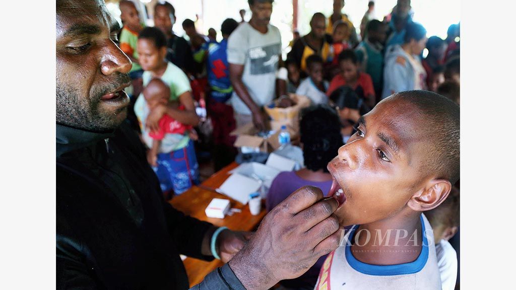 Seorang anak menerima vaksin polio dari Tim Terpadu Penanggulangan KLB Campak dan Gizi Buruk di Kampung Atat, Distrik Pulau Tiga, Kabupaten Asmat, Papua, Sabtu (13/1). Sejak Selasa hingga Sabtu, tim sudah memberikan vaksin campak kepada 400 anak di lima kampung di distrik tersebut.