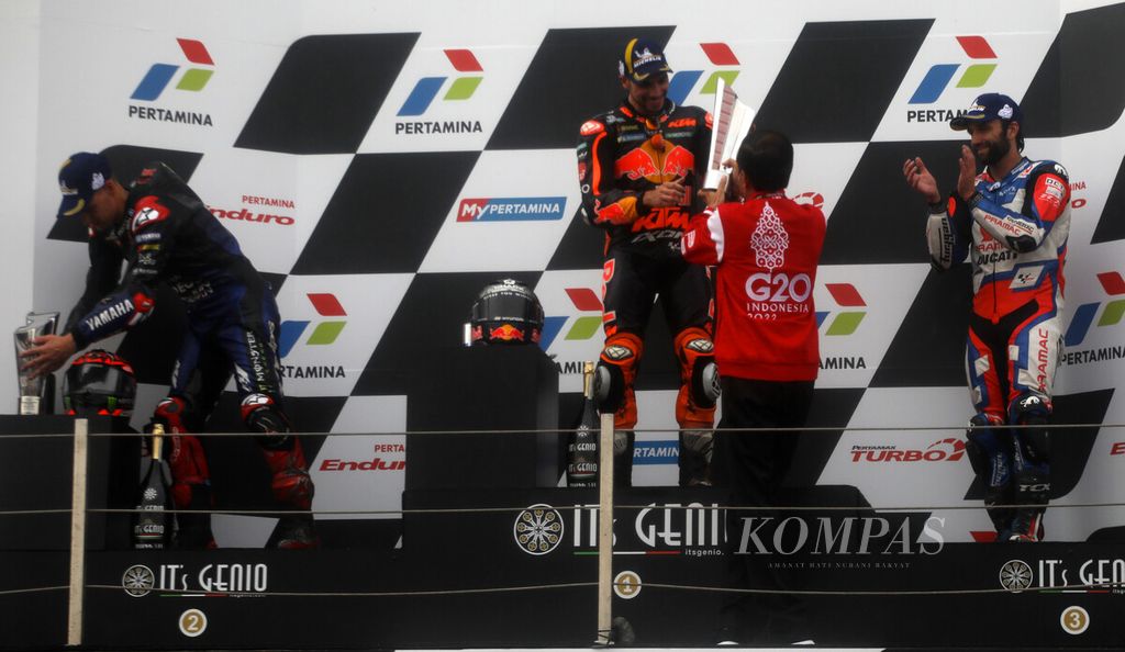 Presiden RI Joko Widodo (kanan) menyerahkan trofi kepada pebalap Red Bull KTM Miguel Oliveira, pemenang pertama Pertamina Grand Prix of Indonesia 2022 di podium Sirkuit Internasional Pertamina Mandalika, Lombok Tengah, NTB, Minggu (20/3/2022). 