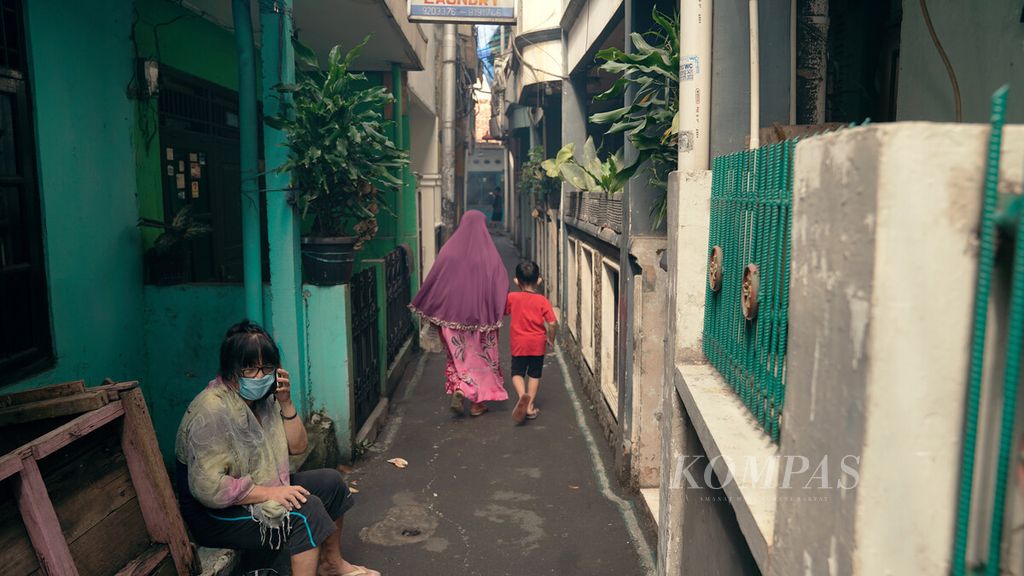 Warga melintasi gang kecil di tengah hunian padat penduduk di Kelurahan Bidara Cina, Kecamatan Jatinegara, Jakarta Timur, Jumat (4/2/2022).