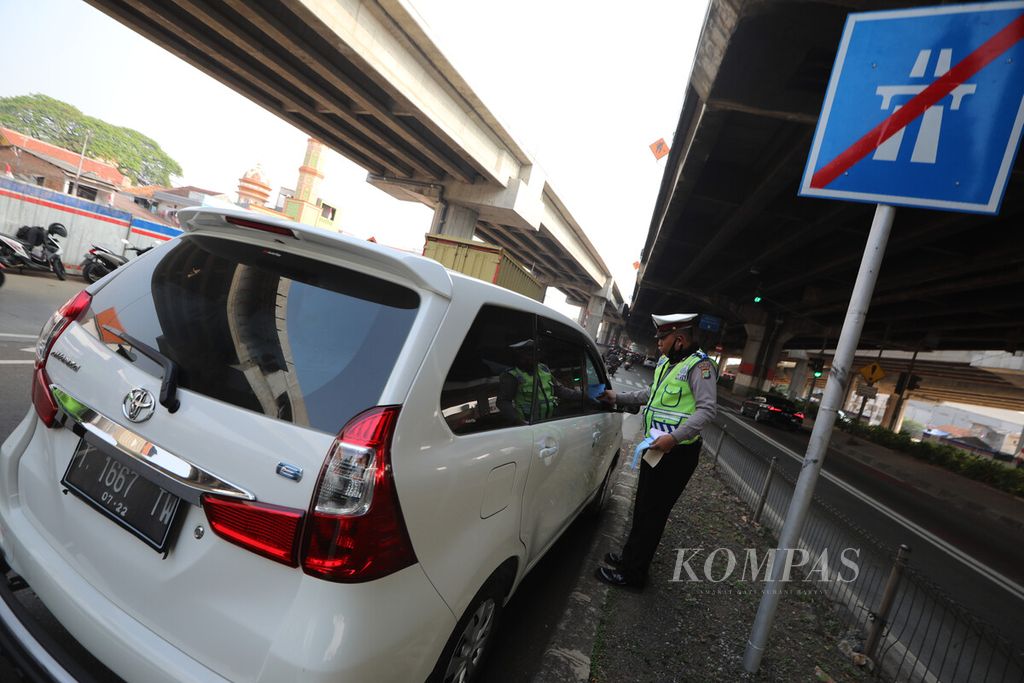 Anggota Direktorat Lalu Lintas Polda Metro Jaya menghentikan mobil yang melanggar aturan ganjil genap di pintu keluar tol DI Pandjaitan, Jakarta Timur, Senin (10/8/2020). 