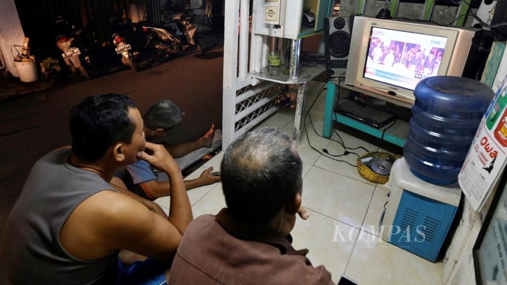 Warga menonton debat pertama capres-cawapres melalui tayangan televisi di poskamling warga di Cengkareng, Jakarta, pertengahan Januari 2019.  