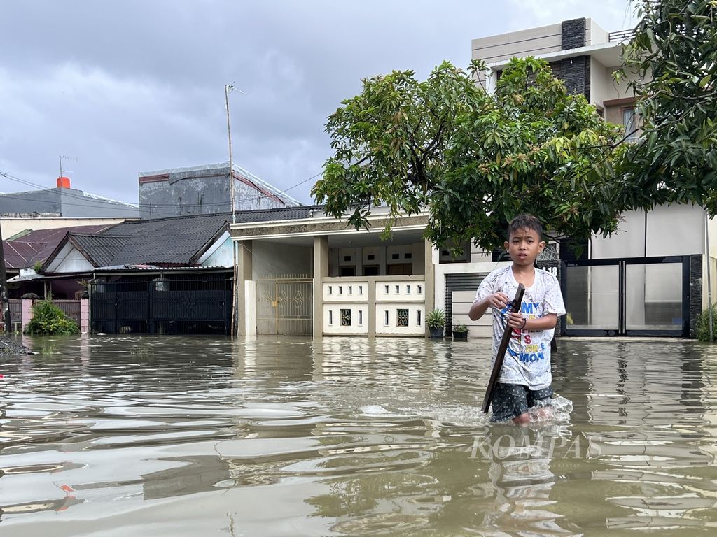 Seorang anak melintasi banjir di Puri Patte’ne, Makassar, Sulawesi Selatan, Selasa (14/2/2023). Walau hujan berangsur reda, kawasan permukiman ini masih terendam.