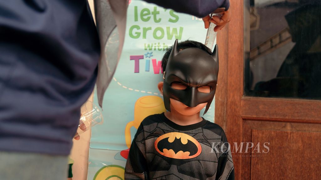Seorang anak mengenakan topeng Batman diukur tinggi badannya saat mengikuti Bulan Imunisasi Anak Nasional (BIAN) dan pneumokokus konjugasi (PCV) di Posyandu Kuntum Mekar, Klender, Jakarta Timur, Kamis (22/9/2022). Sekitar 90 anak mengikuti Bulan Imunisasi Anak Nasional (BIAN) dan PCV di posyandu tersebut. 