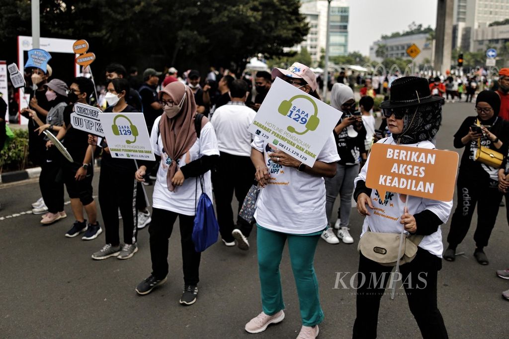  Sambil membawa poster sosialisasi gerakan ”stop kekerasan terhadap perempuan dan anak”, warga mengikuti acara jalan sehat bersama Menteri Pemberdayaan Perempuan dan Perlindungan Anak Bintang Puspayoga di kawasan Bundaran Hotel Indonesia, Jakarta, Minggu (25/9/2022).