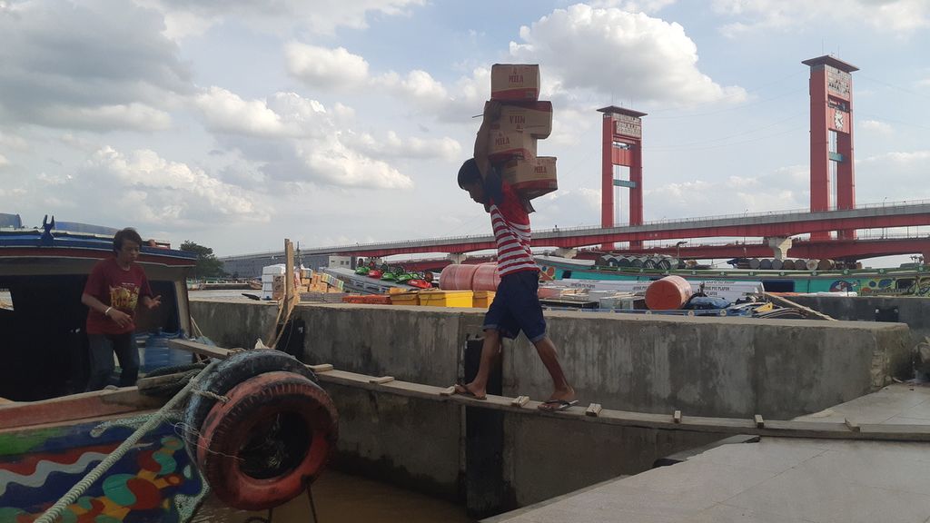 Pekerja membawa barang dari Pasar 16 Ilir ke perahu jukung di pinggiran Sungai Musi, Palembang, Sumsel, Jumat (2/4/2021).