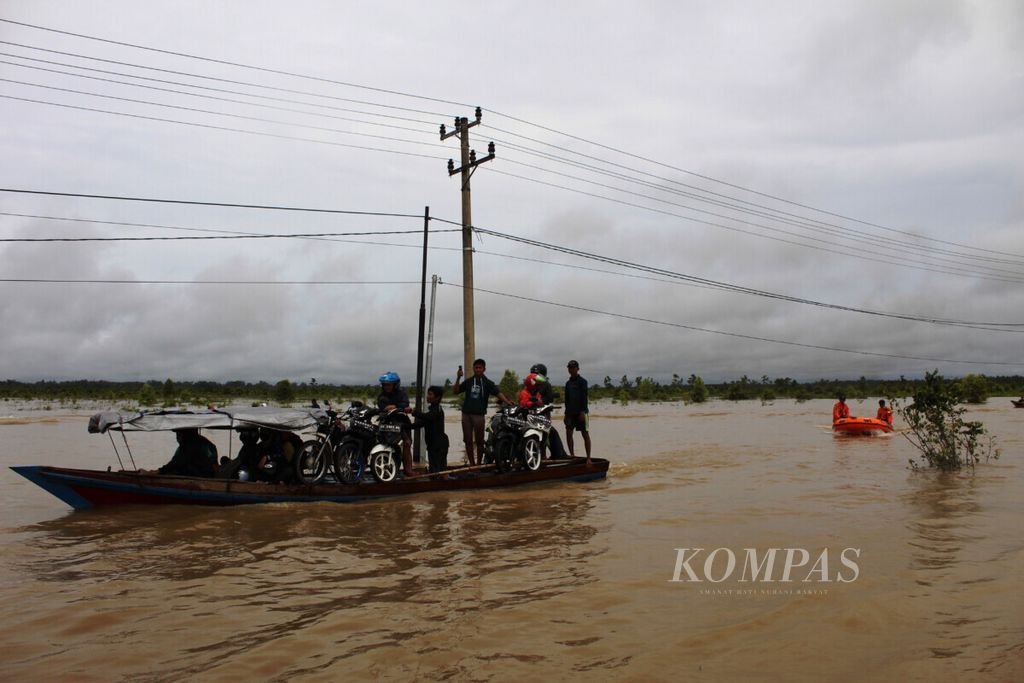 Pengguna jalan Trans-Kalimantan yang menggunakan roda dua menyewa jasa perahu kayu bermotor untuk mengantarkan kendaraan mereka melewati banjir di Bukit Rawi, Kabupaten Pulang Pisau, Kalimantan Tengah, MInggu (14/11/2021). Mereka harus merogoh uang Rp 50.000 untuk menyewa perahu itu.