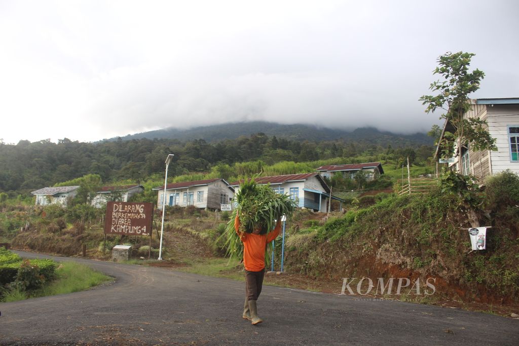 Petani tengah melintas di depan papan peringatan larangan berkemah di Kampung Empat, Kawasan Gunung Dempo, Kota Pagar Alam, Sumatera selatan, Jumat (20/12/2019). Akibat isu harimau, kawasan Gunung Dempo sepi pengunjung.