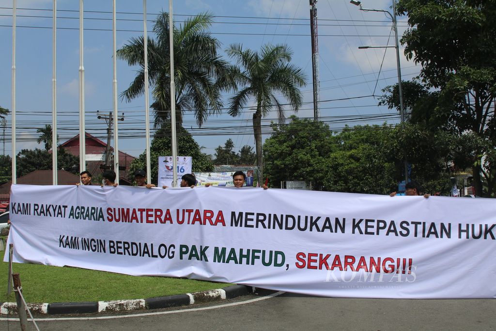 Masyarakat menyambut calon wakil presiden nomor urut 3, Mahfud MD, dengan spanduk tentang kepastian hukum reforma agraria saat tiba di Medan, Sumatera Utara, Minggu (14/1/2024). 