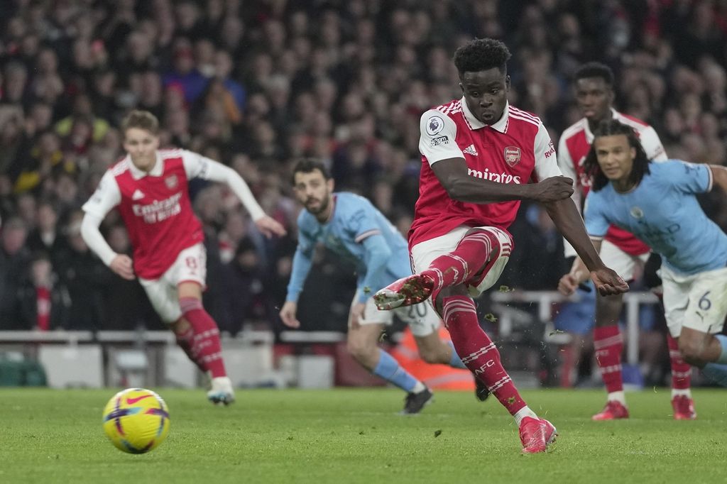 Pemain Arsenal Bukayo Saka (tengah) menendang dari titik penalti untuk mencetak gol ke gawang Manchester City pada laga Liga Inggris di Stadion Emirates, London, Kamis (16/2/2023) dini hari WIB. City menang 3-1 pada laga itu. 