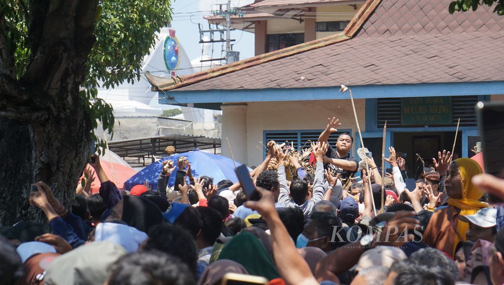 Salah seorang warga memanjat gunungan dan melemparkan segala macam yang tertancap pada gunungan itu ke warga lainnya dalam gelaran Grebeg Maulud di Masjid Agung Keraton Surakarta, Kota Surakarta, Jawa Tengah, Senin (16/9/2024). 