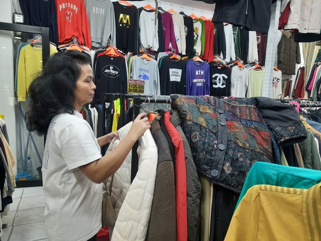 Pedagang pakaian impor bekas, Tia (45), sedang merapikan dagangannya di Metro Pasar Baru, Jakarta, Sabtu (1/4/2023). Ia akan mengikuti regulasi yang ditetapkan pemerintah sembari berharap pemerintah memberikan solusi nyata.