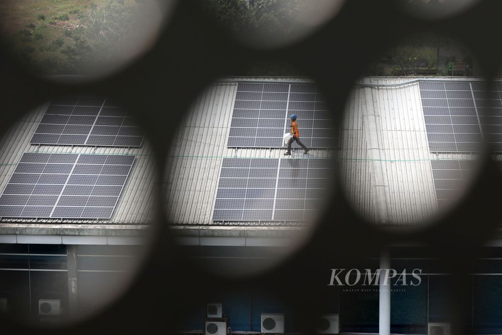 Pekerja berada di atap bangunan yang dipenuhi panel surya di Kampus Universitas Multimedia Nusantara, Kabupaten Tangerang, Banten, Rabu (20/9/2023). Kampus UMN tengah memasang instalasi panel surya sebagai alternatif sumber energi listrik baru dan terbarukan. 