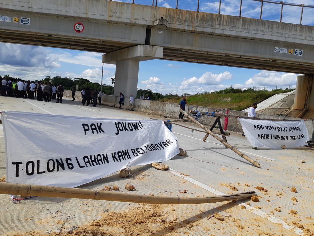 Warga memblokade Jalan Tol Balikpapan-Samarinda Kilometer 6 dengan membentangkan spanduk di tengah jalan di Balikpapan, Kalimantan Timur, Rabu (2/3/2022).