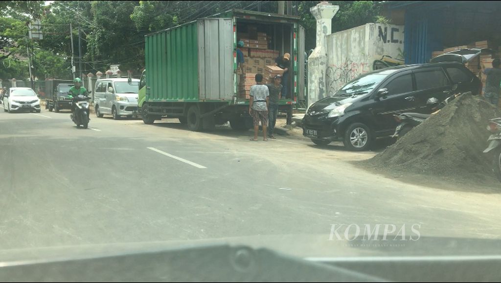 Sejumlah karyawan terlihat sedang menurunkan berdus-dus oli dari sebuah truk di depan toko oli di Cengkareng, Jakarta Barat pada Selasa (18/10/2022).