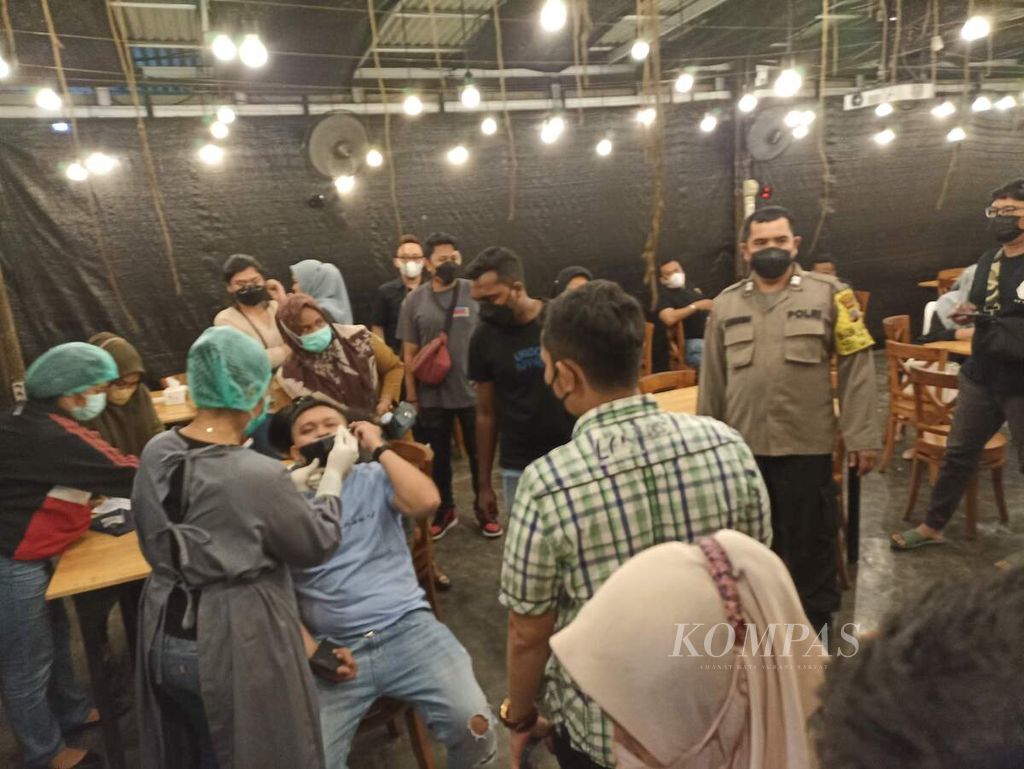 Petugas melakukan tes antigen Covid-19 kepada semua pengunjung sebuah kafe yang melewati batas jam operasional di Medan, Sumatera Utara, Minggu (20/2/2022) malam. Pengetesan dilakukan di sejumlah tempat dengan baru Covid-19 yang sangat tinggi di Medan.