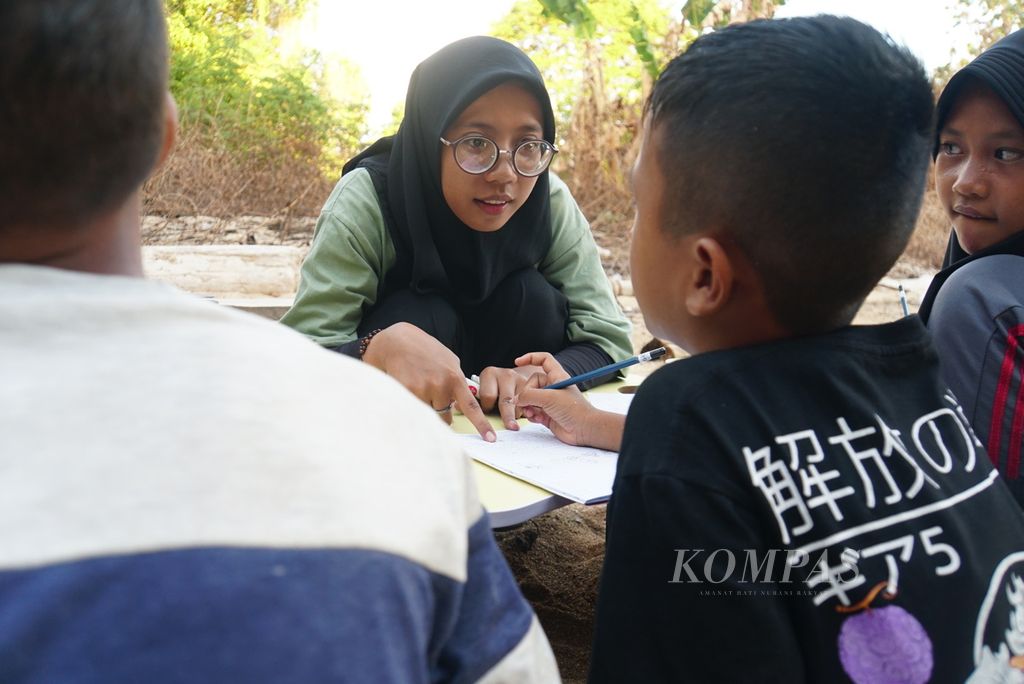Saskia Kirana (20) mengoreksi tulisan murid bernama Rafa (10) dalam kelas informal baca-tulis yang diselenggarakan komunitas literasi Aksara Manado, Sabtu (18/11/2023), di Pulau Bunaken, Manado, Sulawesi Utara. 