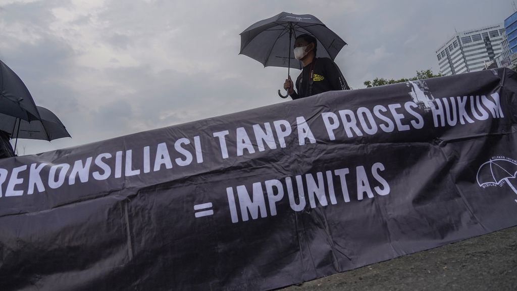 Seorang aktivis dan sebuah spanduk yang dipasang dalam Aksi Kamisan di depan Istana Merdeka, Jakarta, Kamis (1/12/2022). 