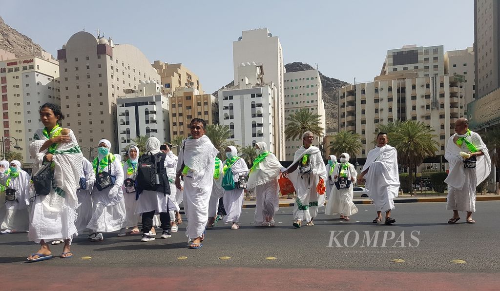 Sejumlah anggota jemaah haji Indonesia sedang menyeberang jalan di kawasan Mahbas Jin di Mekkah, Arab Saudi, Sabtu (18/6/2022) siang. Untuk memastikan keamanan jemaah, petugas haji Indonesia membantu proses penyeberangan dari halte bus menuju hotel.