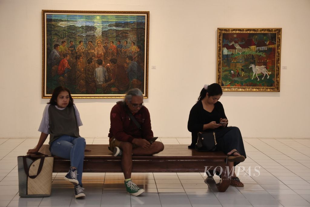 Sejumlah pengunjung di depan lukisan karya Amrus Natalsya dan Misbach Tamrin yang ditampilkan dalam pameran <i>Dua Petarung</i> di Bentara Budaya Yogyakarta, Kota Yogyakarta, Jumat (15/12/2023). 