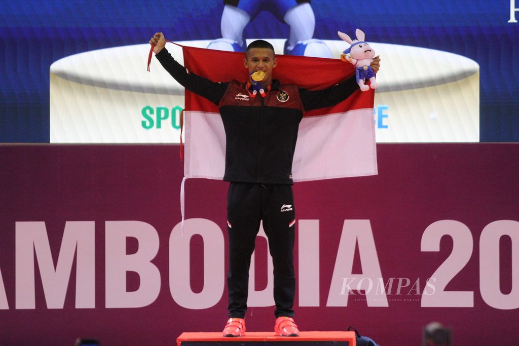 Rizki Juniansyah, lifter muda Indonesia menunjukkan medali emas yang ia raih seusai memecahkan rekor dengan total angkatan 347 kilogram (<i>snatch </i>156 kg dan <i>clean and jerk</i> 347 kg) di cabang angkat besi kelas putra 73 kilogram di National Olympic Stadium, Kamboja, Minggu (14/5/2023).