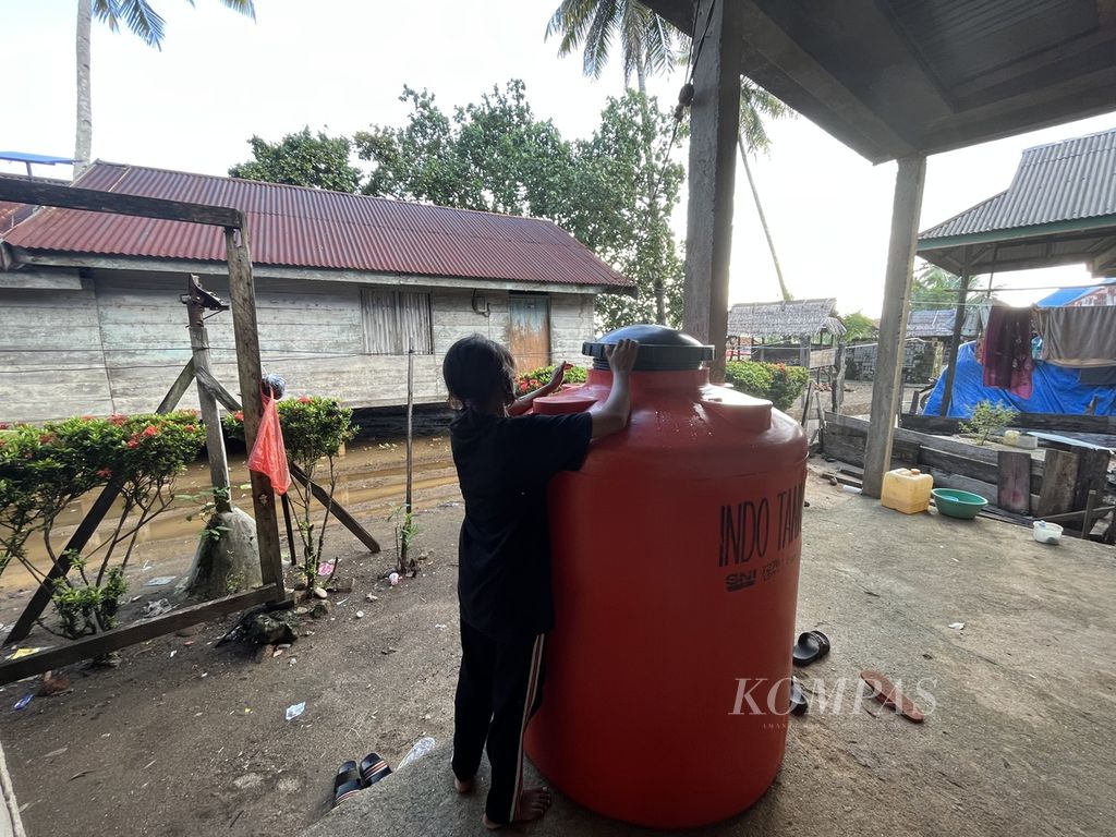 Irdawati (17) mengecek tampungan air hujan di depan rumahnya di Desa Sukarela Jaya, Wawonii Tenggara, Konawe Kepulauan, Sultra, Kamis (1/6/2023). Hampir sebulan terakhir warga kesulitan mendapatkan air bersih karena mata air mereka tercemar lumpur.