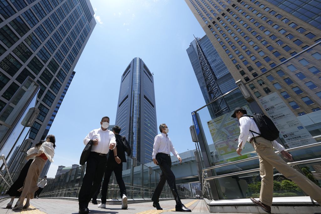 Para pejalan kaki menyusuri sebuah ruas jalan dengan latar belakang gedung-gedung pencakar langit di Tokyo, Jepang, 13 Juni 2022. 