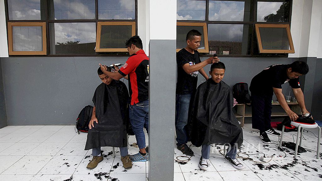Para peserta kursus pangkas rambut Baraya Desa dari Desa Banyuresmi, Garut, memangkas rambut para siswa SMK Negeri 2 Garut, Garut, Jawa Barat, Rabu (18/10). 