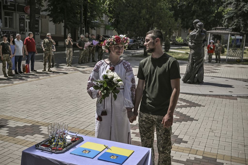 Kristina (kanan) dan Vitaliy Orlich, keduanya tentara Ukraina yang aktif bertugas, menikah di kota Druzhkivka, wilayah Donbas, Ukraina timur, 12 Juni 2022. 