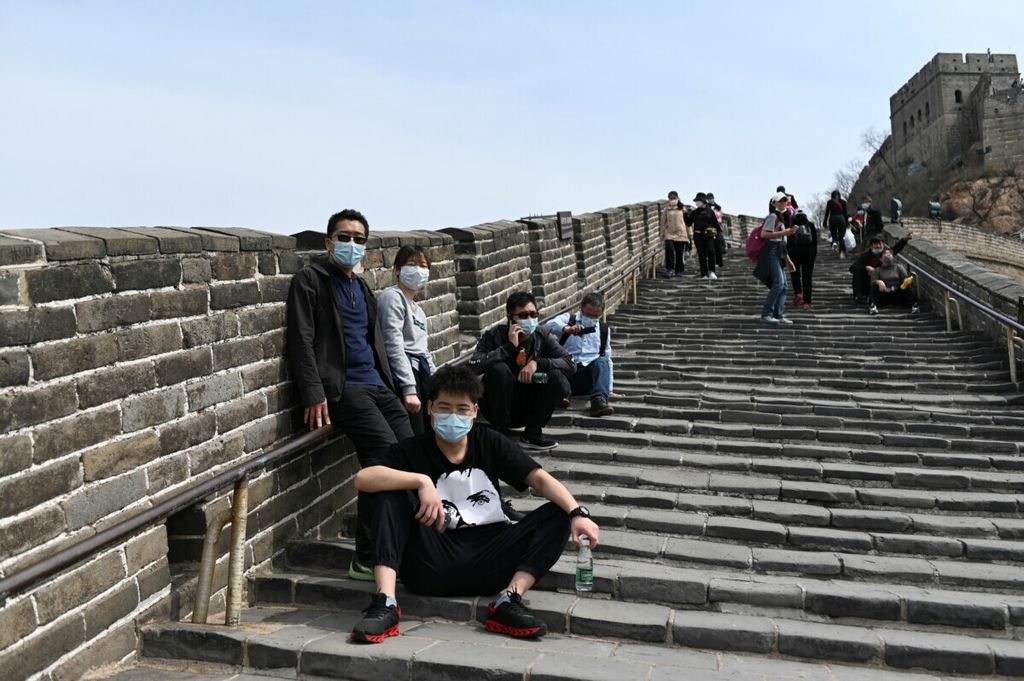 Sekelompok wisatawan mengenakan masker di tengah kekhawatiran virus Covid-19 saat mengunjungi Tembok Besar China di Beijing pada (18/4/2020).