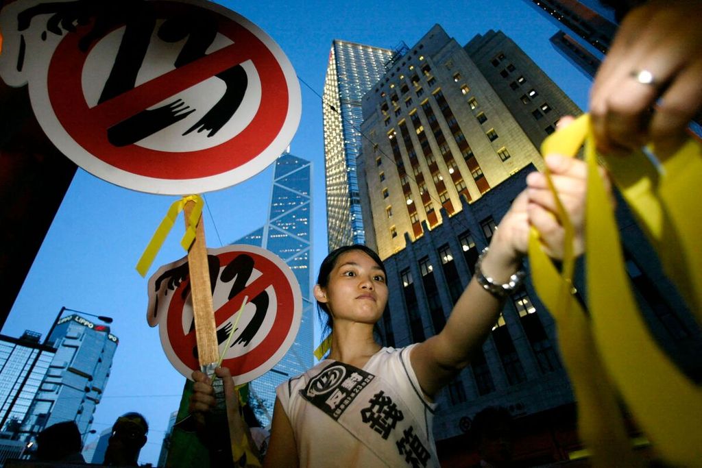 Tampak dalam foto bertanggal 9 Juli 2003, seorang aktivis membagikan pita kuning saat unjuk rasa memprotes Undang-Undang Keamanan atau Pasal 23. Pekan ini, pada 19 Maret 2024, Pemerintah Hong Kong mengesahkan undang-undang tersebut dan memberlakukannya mulai 23 Maret 2024. 