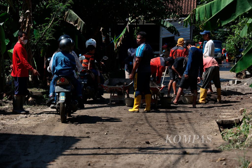 Petugas gabungan membersihkan akses jalan yang tertutup lumpur karena banjir di Kampung Rowosari, Kecamatan Tembalang, Kota Semarang, Jawa Tengah, Minggu (19/2/2023). 