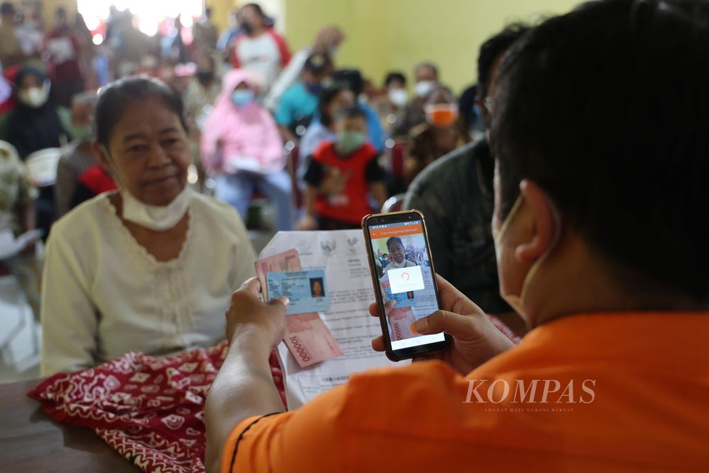 Petugas memotret warga yang mengambil dana Bantuan Langsung Tunai setelah mengikuti vaksinasi Covid-19 penguat di kantor Desa Ngrundul, Kebonarum, Klaten, Jawa Tengah, 18 April 2022. 