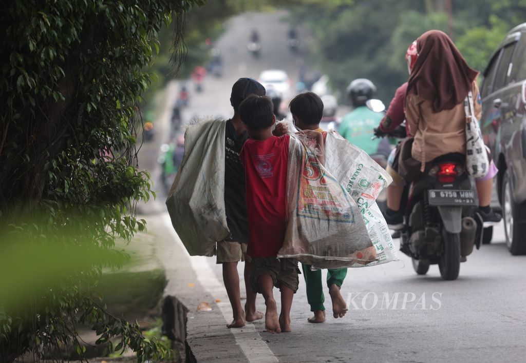 Alief, Rangga, dan Goran (kiri ke kanan) memulung barang bekas di Jalan Raya Puspitek, Buaran, Tangerang Selatan, Banten, 29 Maret 2023. Dari bertiga, hanya Rangga yang mengenyam pendidikan sekolah dasar. Alif dan Goran tidak bersekolah sama sekali. 