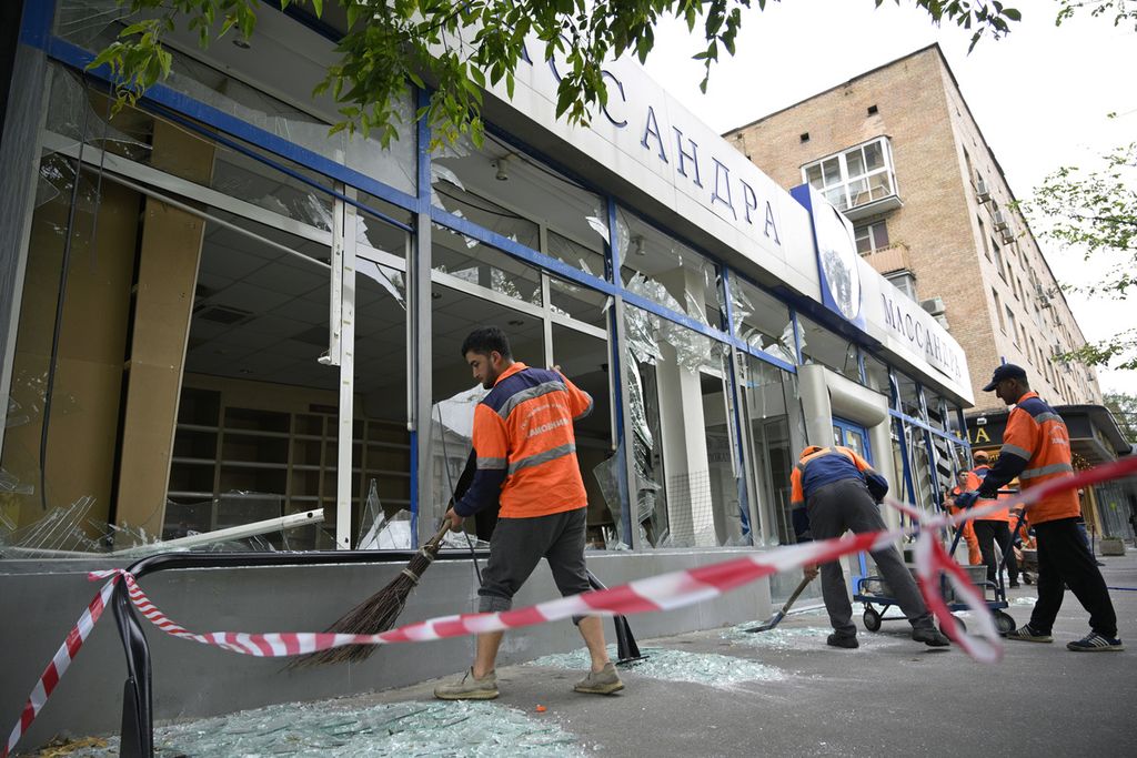 Sejumlah pekerja menyapu pecahan kaca jendela sebuah gedung yang rusak pasca serangan pesawat tak berawak Ukraina atas Moskwa pada Senin (24/7/2023).