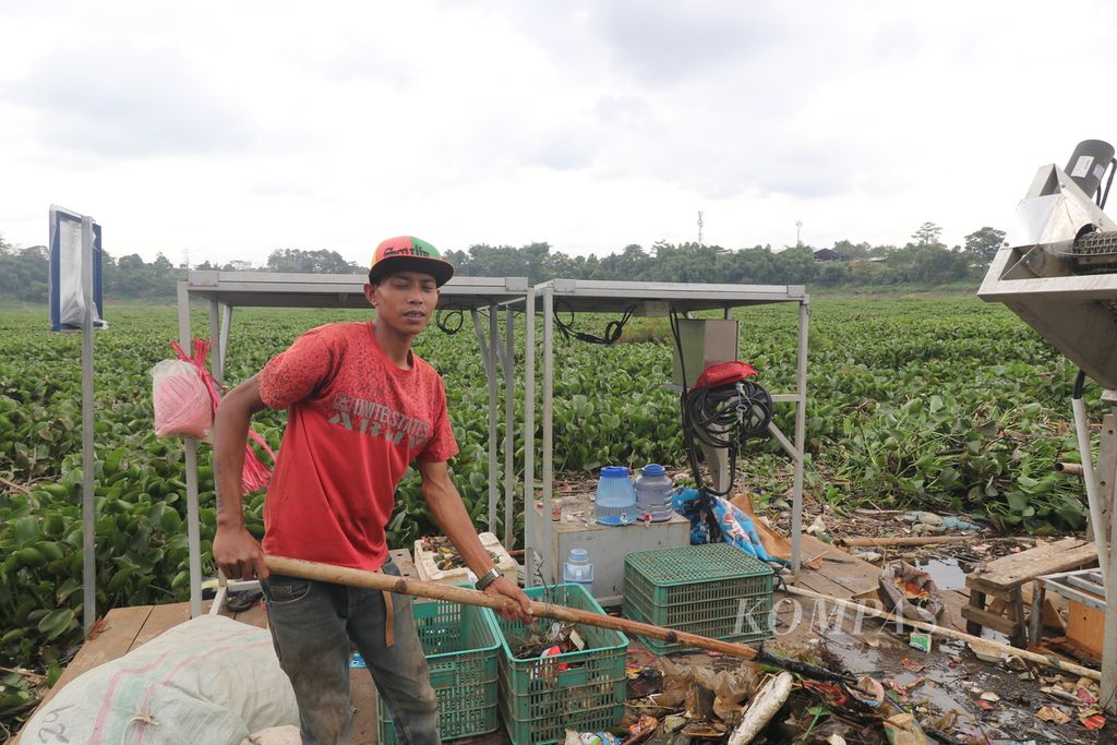 Petugas kebersihan Bening Saguling Foundation Rudi sedang mengambil sampah yang tertahan di aliran Sungai Citarum, Selasa (7/2/2023). Rudi merupakan warga Cihampelas, Kabupaten Bandung, yang sebelumnya merupakan pemulung, tetapi kini menjadi bagian Bening Saguling Foundation sebagai petugas kebersihan.