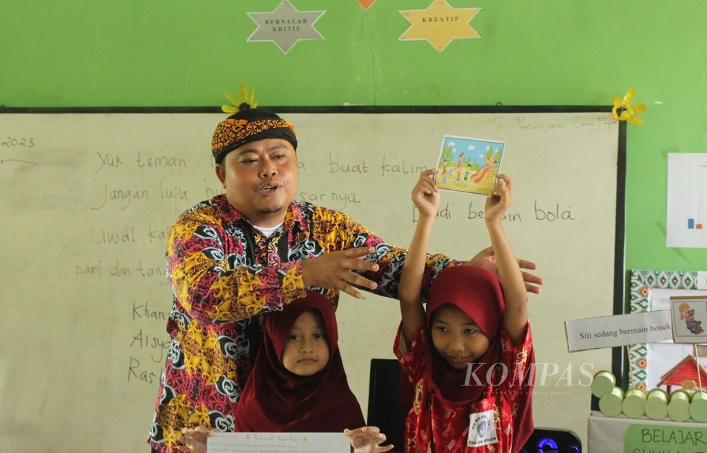 Sudarmuji (35), guru kelas II Sekolah Dasar Negeri 026 Tanjung Selor, Kabupaten Bulungan, Kalimantan Utara, mengajar siswanya menulis cerita, Kamis (13/4/2023).