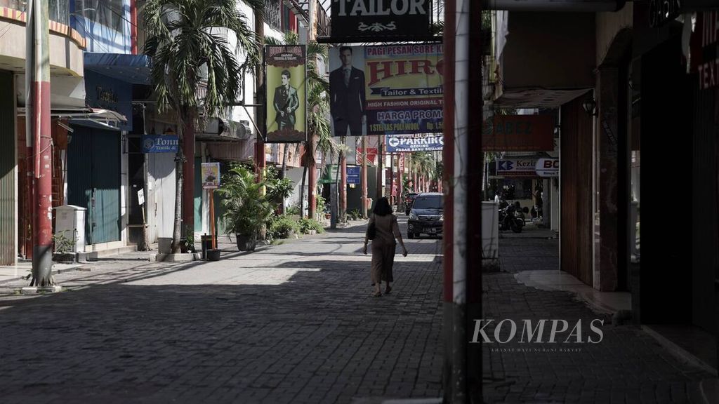 Warga melintas di pertokoan yang tutup di Pasar Baru, Jakarta Pusat, Selasa (31/3/2020). 