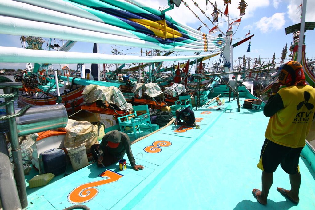 Sejumlah nelayan mengecat bagian lantai kapal ketika kapal mereka bersandar di Pelabuhan Muncar, Banyuwangi, Jumat (2/10/2020). Saat bulan purnama, para nelayan memilih tidak melaut dan memanfaatkan waktu untuk memperbaiki kapal dan alat tangkap.