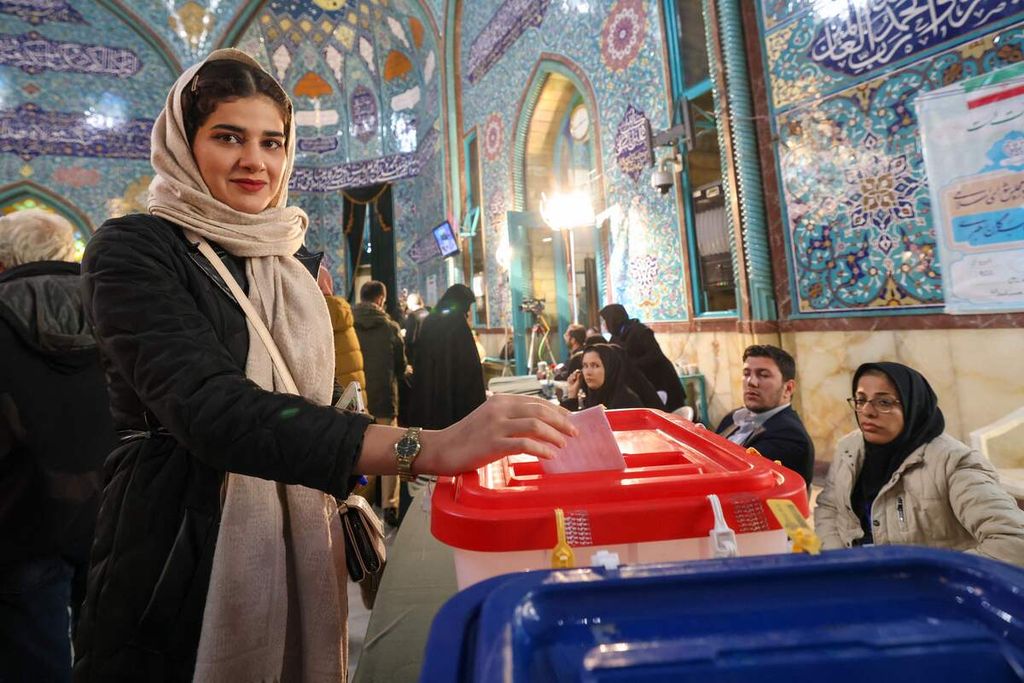 Seorang perempuan warga Iran memasukkan kertas suaranya di kotak suara dalam pemilihan umum legislatif dan Majelis Pakar di sebuah tempat pemungutan suara di Teheran, Iran, Jumat (1/3/2024). 