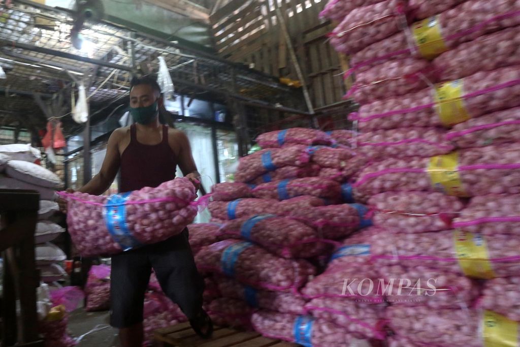 Pekerja menyiapkan bawang putih pesanan pelanggan, Kamis (14/5/2020), di Pasar Induk Kramatjati, Jakarta, Kamis (14/5/2020). 
